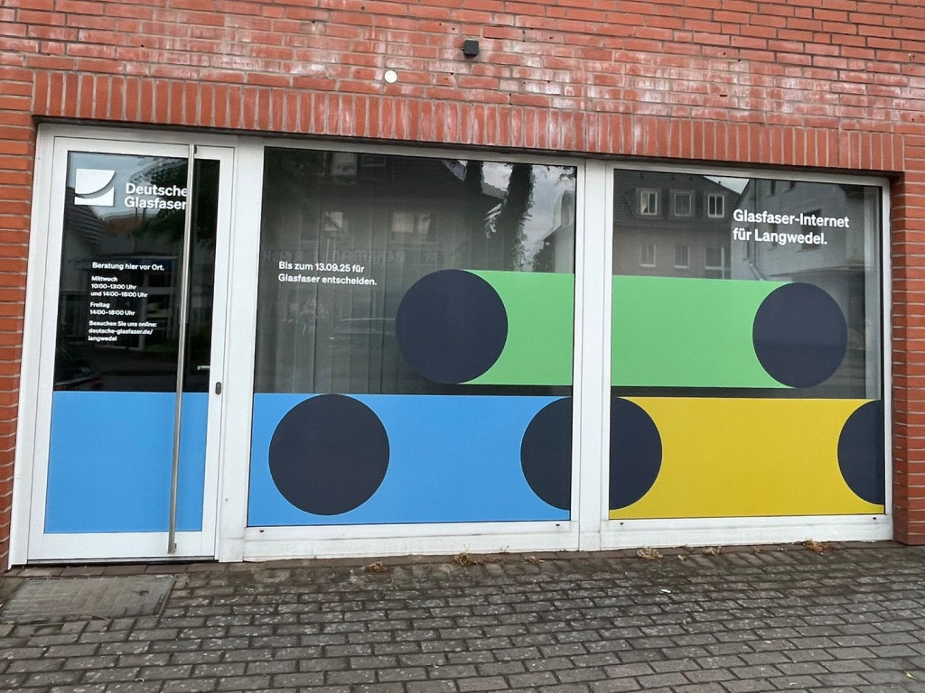 Bunte Fensterfolierung mit Designelementen, Logo und Öffnungszeiten als Werbetechnik.